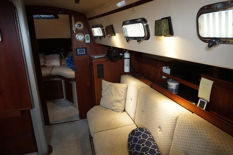 Slide: The Image of Interior of a 1994 Island Packet 32 sailboat, featuring a cozy cabin with seating and portholes. - 18