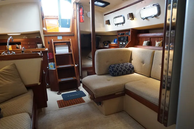Slide: The Image of Interior of a 1994 Island Packet 32 sailboat, featuring cozy seating and wooden accents. - 25