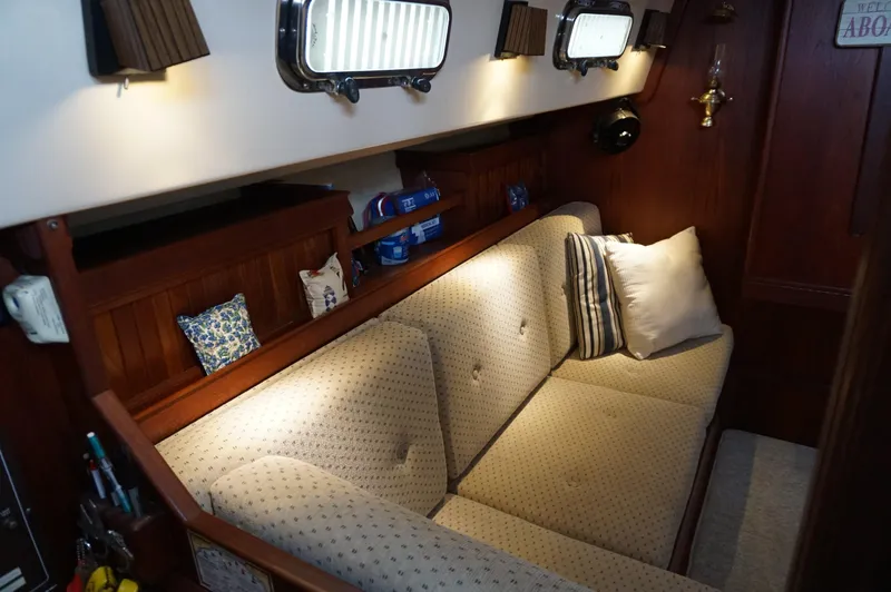 Slide: The Image of Interior of 1994 Island Packet 32 sailboat with cushioned seating and wooden accents. - 27