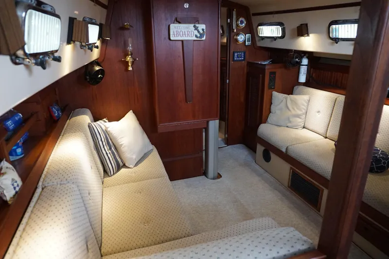 Slide: The Image of Interior of a 1994 Island Packet 32 sailboat, featuring cozy seating and wooden accents. - 28