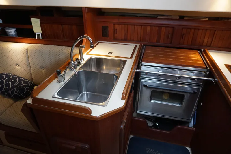 Slide: The Image of 1994 Island Packet 32 yacht kitchen with sink, stove, and wooden cabinetry. - 31