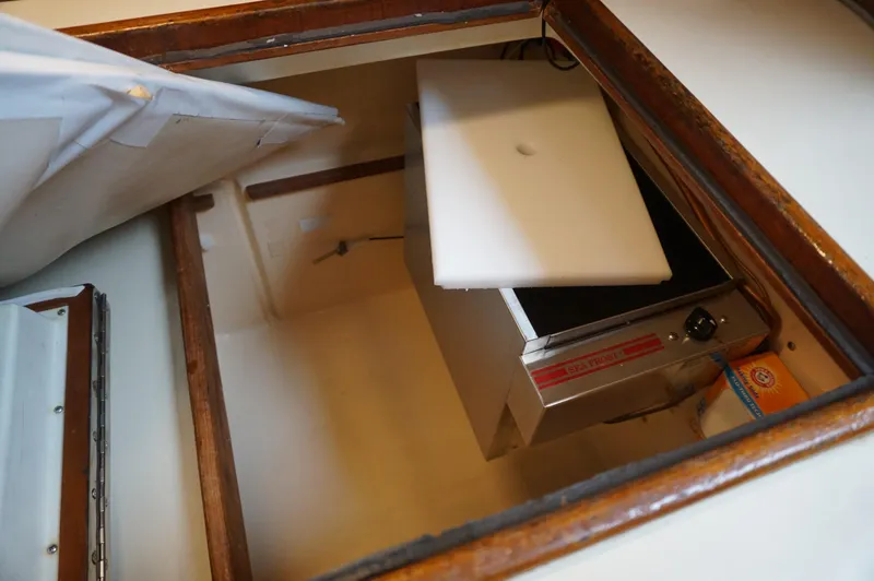 Slide: The Image of Storage compartment in a 1994 Island Packet 32 sailboat, featuring a built-in refrigerator. - 32