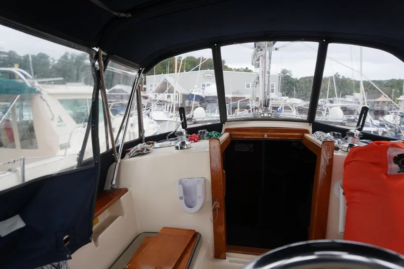 Slide: The Image of 1994 Island Packet 32 sailboat cockpit with marina view, featuring wooden accents and protective canopy. - 41