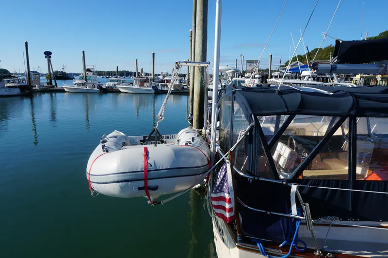 Slide: The Image of Sailboat Island Packet 32 (1994) docked with dinghy, marina background, clear sky. - 7