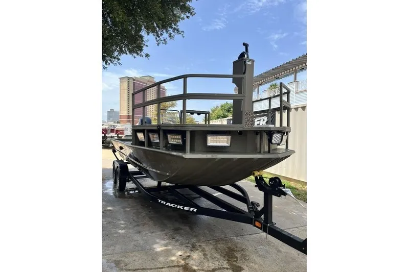 Slide: The Image of 2025 Tracker Grizzly 2072 CC Sportsman Kicker boat on trailer, urban background. - 7