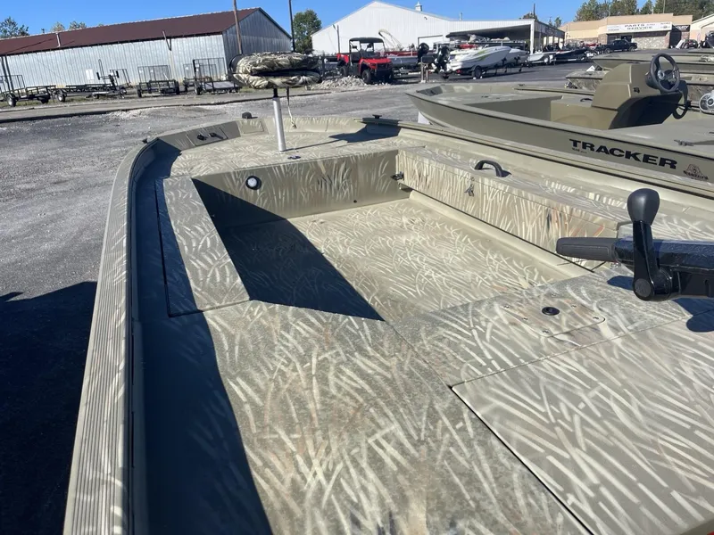 Slide: The Image of 2025 Tracker Grizzly 1654 T Sportsman boat with camouflage interior in a marina setting. - 6