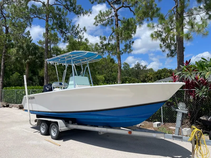 The Image of 1995 Contender 21 Open boat on trailer, parked outdoors under blue sky. - 1