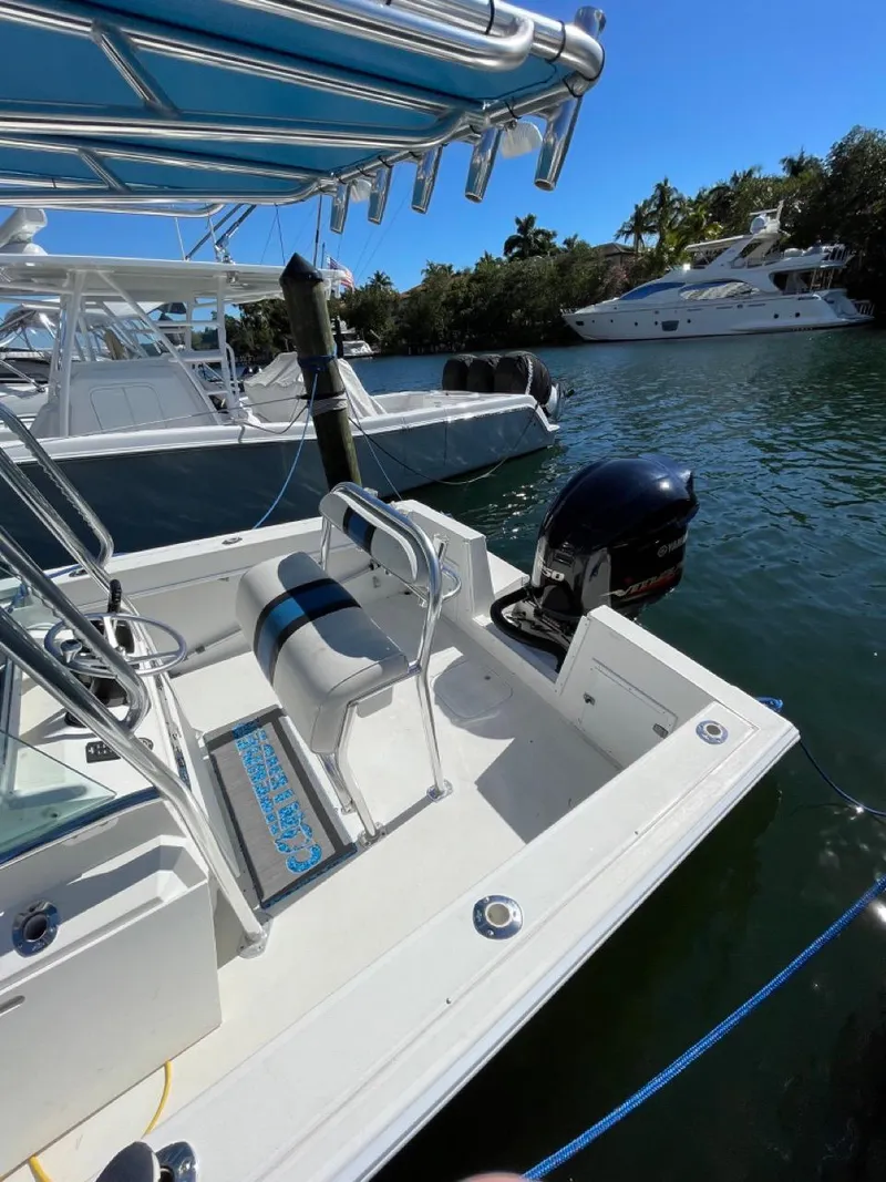 Slide: The Image of 1995 Contender 21 Open boat docked in a sunny marina, featuring a sleek design and outboard motor. - 5