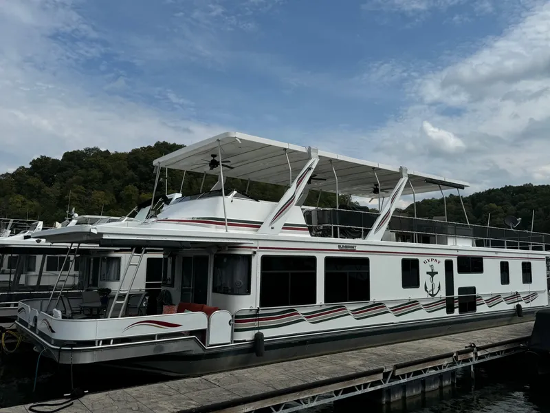 Slide: The Image of 1999 Sumerset 16 X 80 houseboat docked, featuring a spacious upper deck and scenic surroundings. - 2