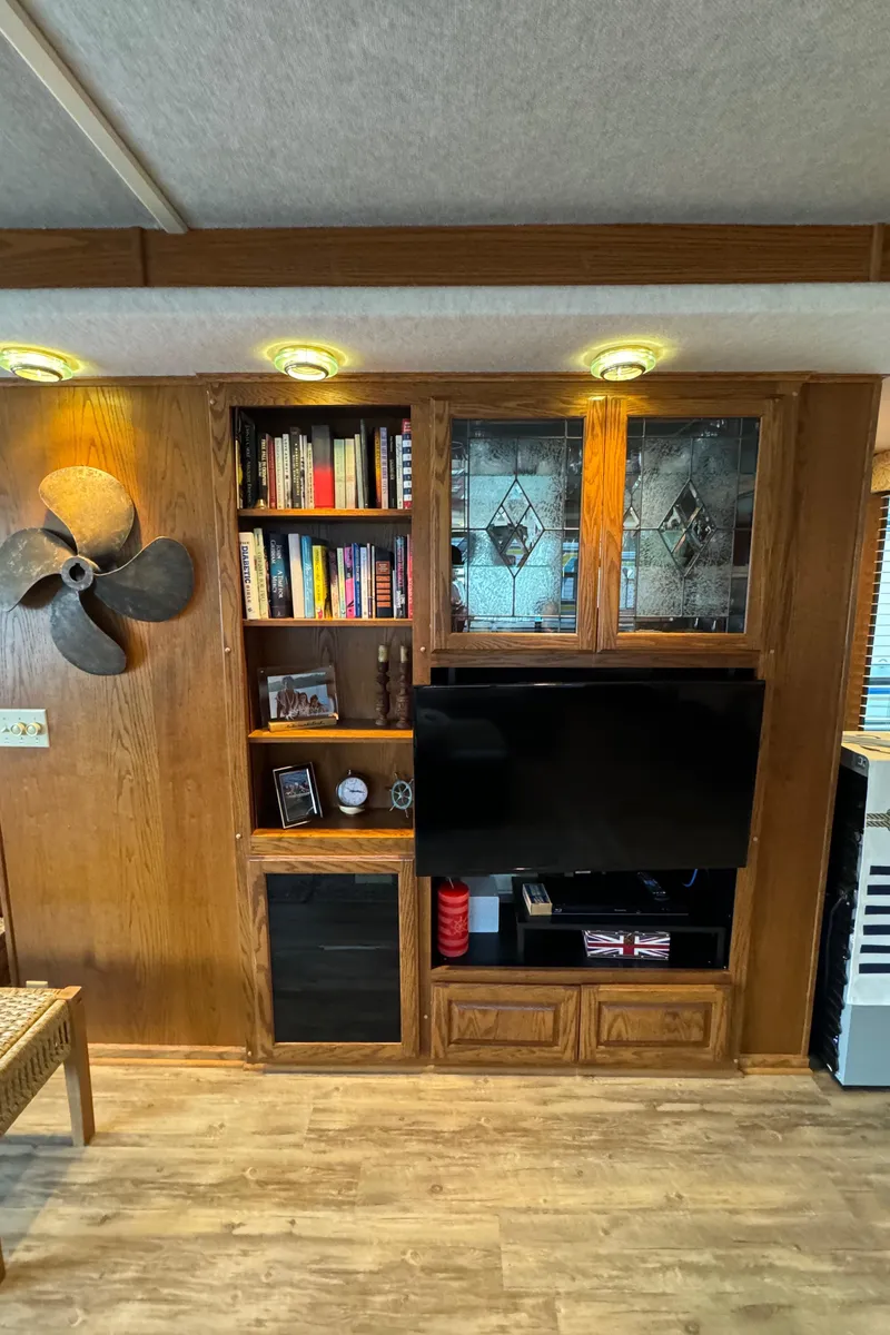 Slide: The Image of 1999 Sumerset 16 X 80 houseboat interior with wooden entertainment center and decorative shelving. - 26