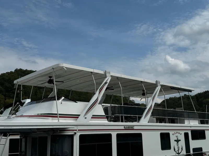 Slide: The Image of 1999 Sumerset 16 X 80 houseboat with canopy, docked under a partly cloudy sky. - 3