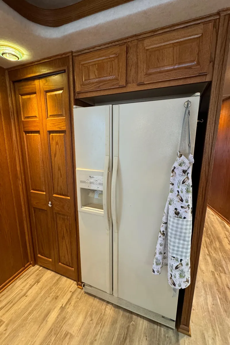 Slide: The Image of 1999 Sumerset 16 X 80 houseboat kitchen with wooden cabinets and a white refrigerator. - 31