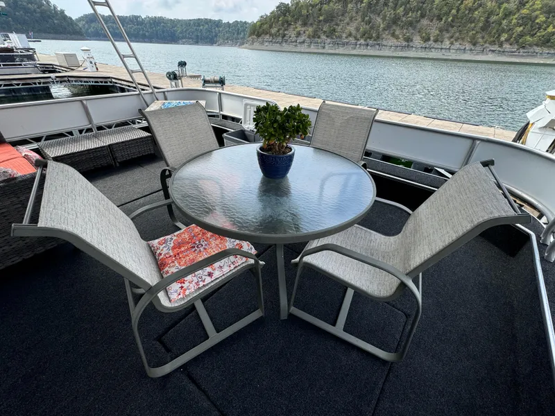 Slide: The Image of Outdoor seating on a Sumerset 16 X 80 houseboat, featuring a glass table and chairs, 1999 model. - 4