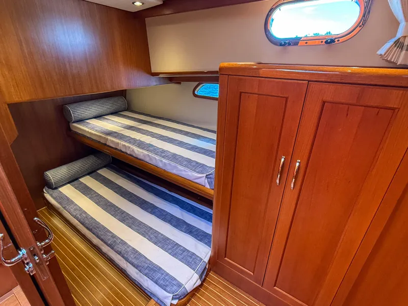 Slide: The Image of 2014 Grand Banks 50 Eastbay SX cabin with twin striped beds and wooden cabinetry. - 25