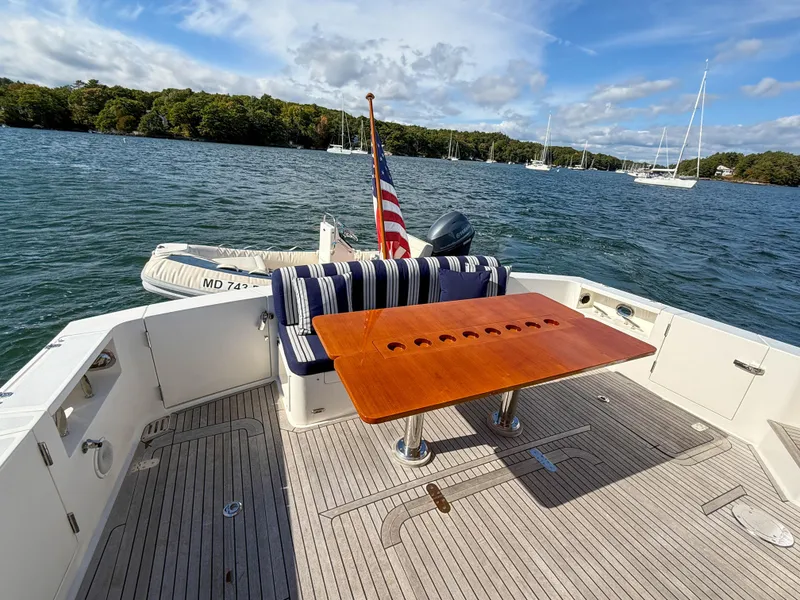 Slide: The Image of 2014 Grand Banks 50 Eastbay SX yacht deck with table, seating, and scenic water view. - 7