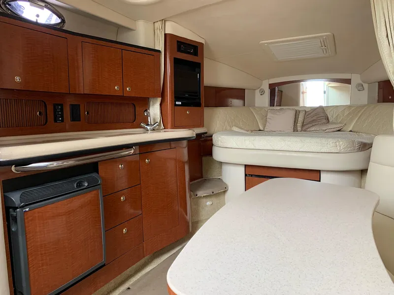 Slide: The Image of Interior of 2004 Sea Ray 320 Sundancer with wood cabinetry and cozy seating area. - 13