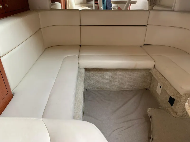 Slide: The Image of 2004 Sea Ray 320 Sundancer interior with beige leather seating and carpeted flooring. - 14