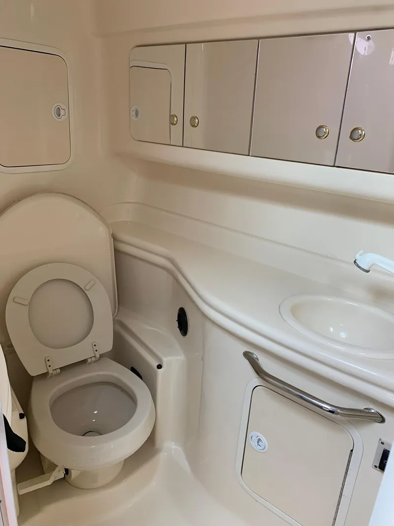 Slide: The Image of 2004 Sea Ray 320 Sundancer bathroom with toilet, sink, and storage cabinets. - 16