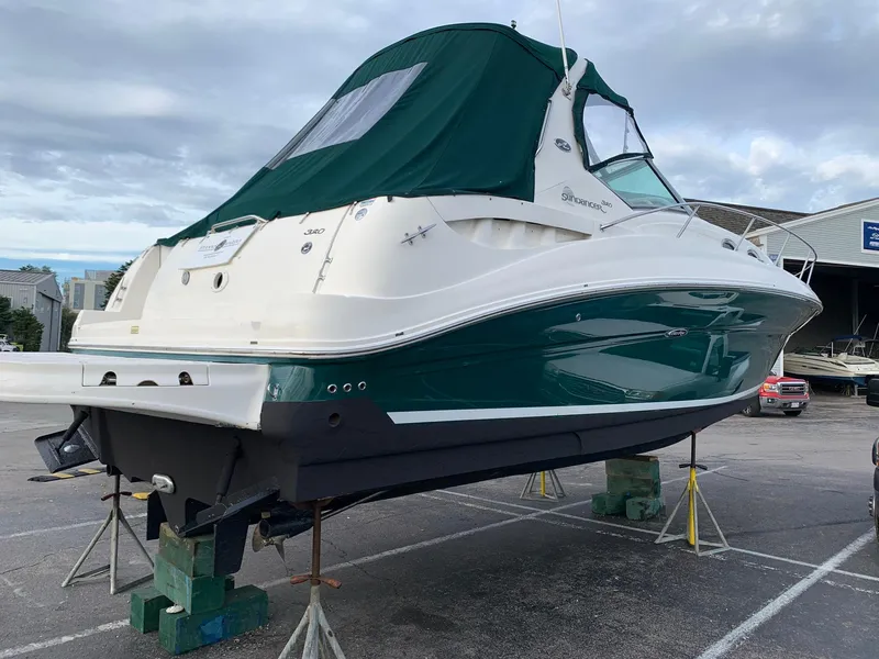 Slide: The Image of 2004 Sea Ray 320 Sundancer boat on dry dock with green canopy. - 2