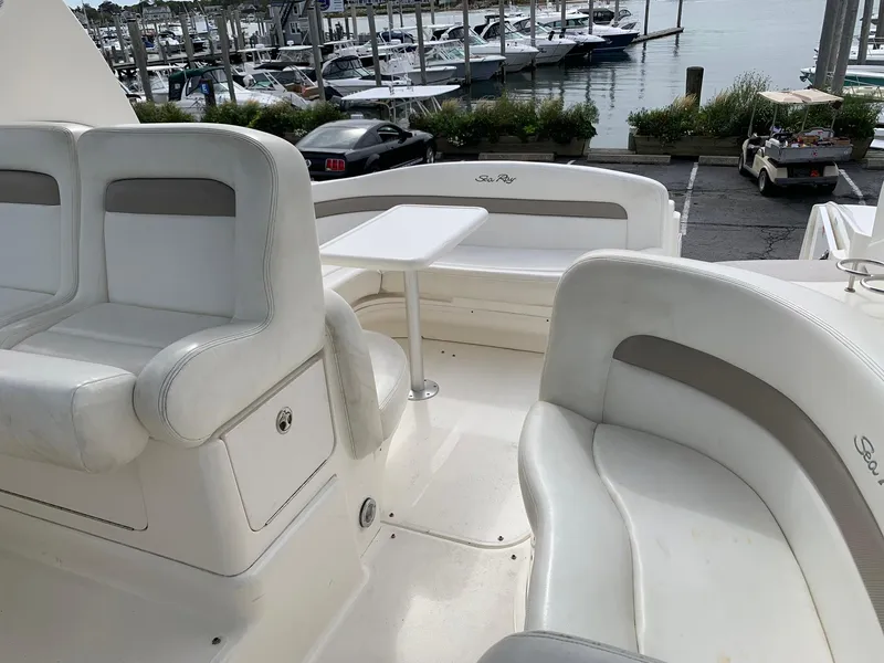 Slide: The Image of 2004 Sea Ray 320 Sundancer boat interior with white seating and table, docked at marina. - 9
