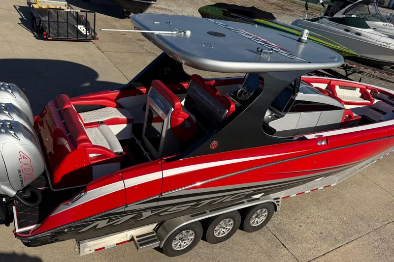 Slide: The Image of 2019 Mystic Powerboats M3800, red and black design, triple outboard engines, on a trailer. - 20