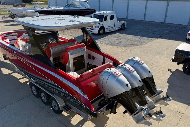 Slide: The Image of 2019 Mystic Powerboats M3800 with triple outboard engines, red and black design, parked on trailer. - 22