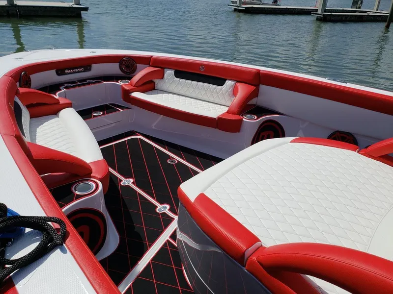 Slide: The Image of 2019 Mystic Powerboats M3800 interior with red and white seating, docked on calm water. - 6