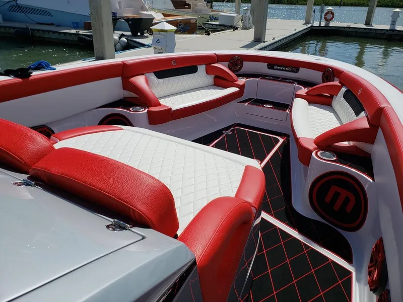 Slide: The Image of 2019 Mystic Powerboats M3800 interior with red and white seating, docked at marina. - 9