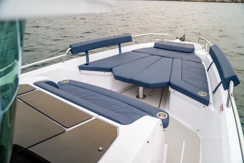 Slide: The Image of 2025 Axopar 29 XC Cross Cabin boat with blue seating on calm water. - 11