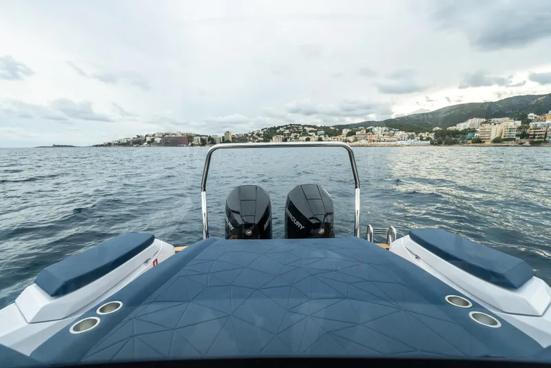 Slide: The Image of 2025 Axopar 29 XC Cross Cabin on water, dual engines, coastal cityscape in background. - 16