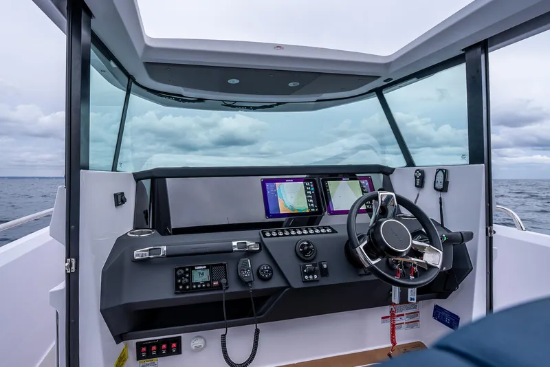 Slide: The Image of 2025 Axopar 29 XC Cross Cabin helm with modern navigation equipment and steering wheel. - 5