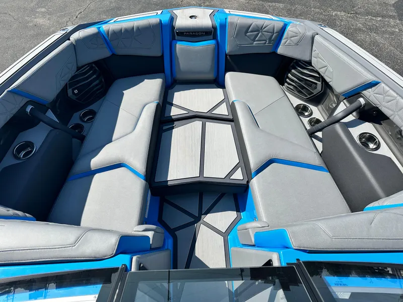 Slide: The Image of 2025 Nautique G23 Paragon boat interior with gray and blue seating, cup holders, and speakers. - 16