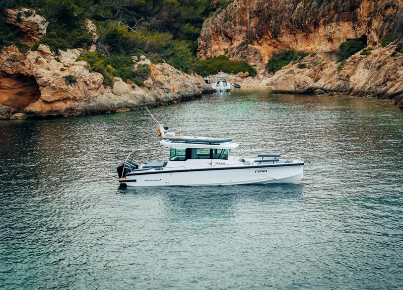 Slide: The Image of 2025 Axopar 29 XC Cross Cabin boat in a scenic rocky cove. - 2