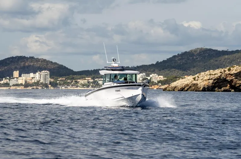 Slide: The Image of 2025 Axopar 29 XC Cross Cabin cruising on open water, scenic coastal backdrop. - 3