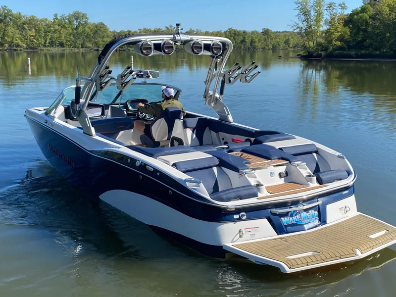 Slide: The Image of 2018 MasterCraft X26 boat on a calm lake with lush greenery. - 10