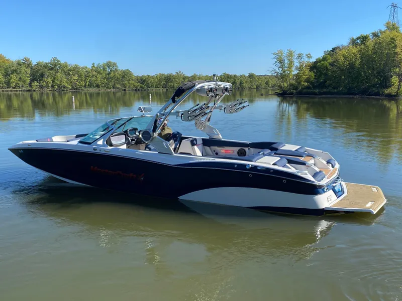 Slide: The Image of 2018 MasterCraft X26 boat on a calm lake, surrounded by trees. - 11