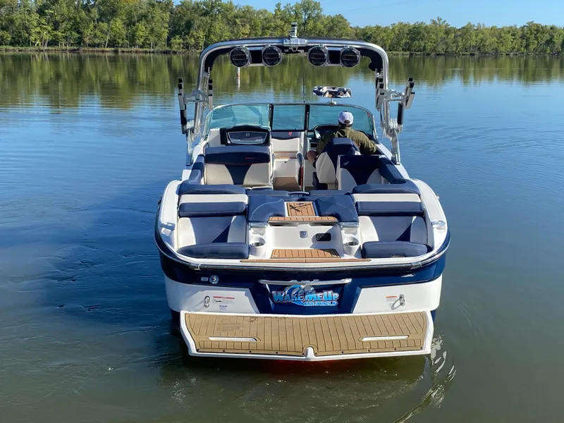 Slide: The Image of 2018 MasterCraft X26 boat on calm lake with lush green shoreline. - 15