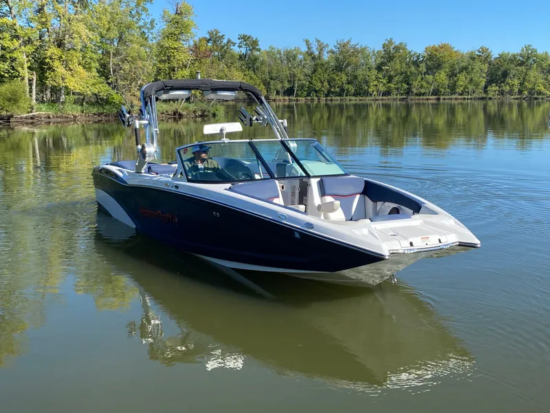 Slide: The Image of 2018 MasterCraft X26 boat on a calm lake with trees in the background. - 5