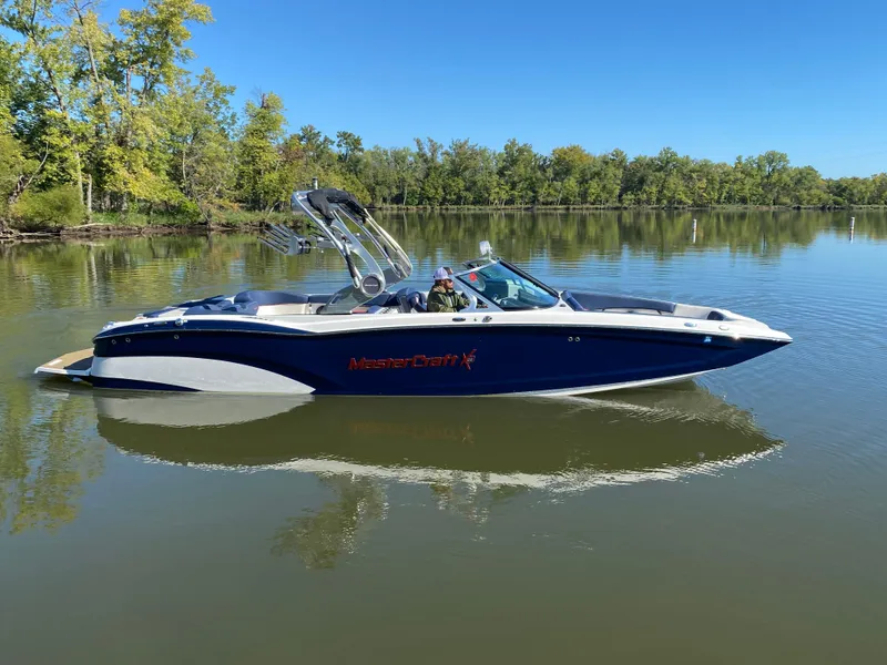 Slide: The Image of 2018 MasterCraft X26 boat on a calm lake with trees in the background. - 8
