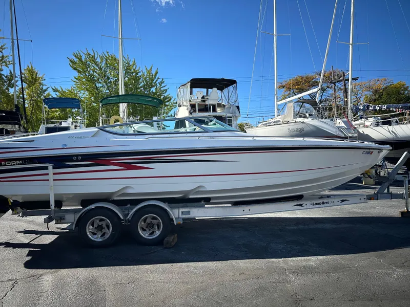 Slide: The Image of 2004 Formula 292 FASTech boat on trailer, parked in marina with sailboats in background. - 13