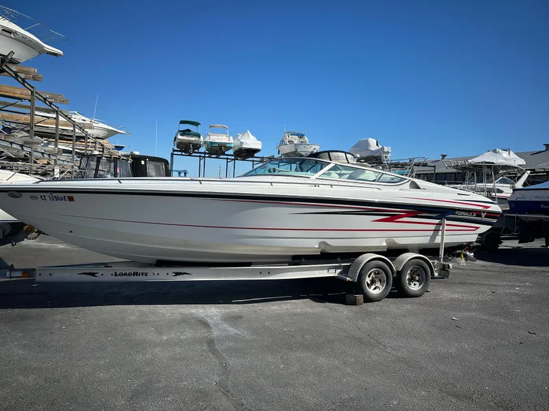 Slide: The Image of 2004 Formula 292 FASTech boat on trailer, parked in marina under clear blue sky. - 4
