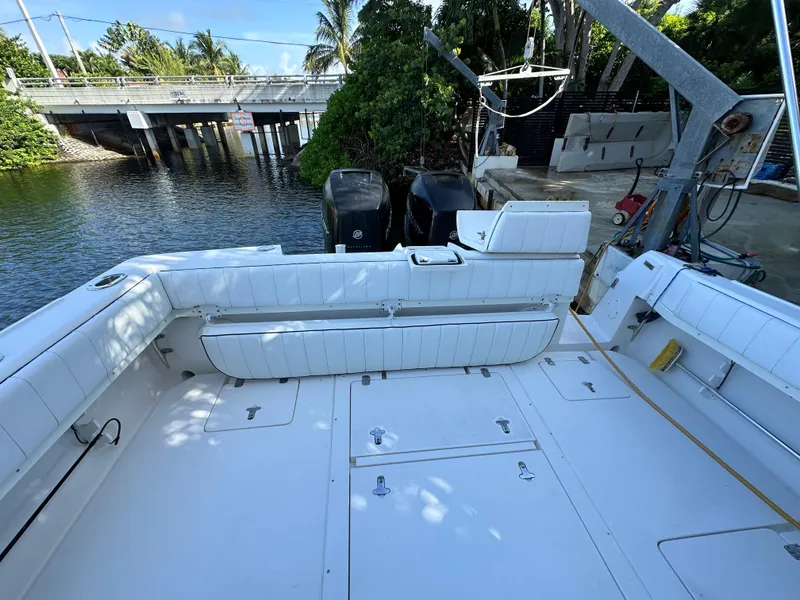 Slide: The Image of 2005 Intrepid 348 WA boat with spacious deck, docked near a bridge and lush greenery. - 7