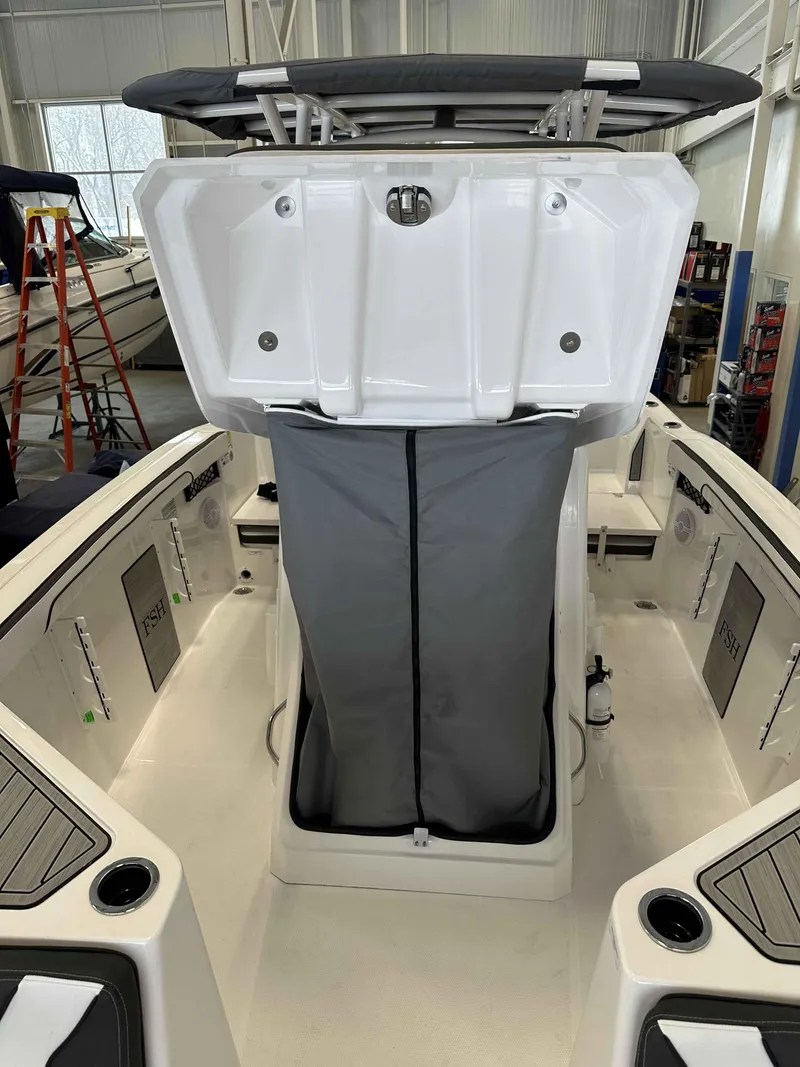 Slide: The Image of 2025 Yamaha Boats 222 FSH Sport interior with storage compartment open in a showroom. - 21
