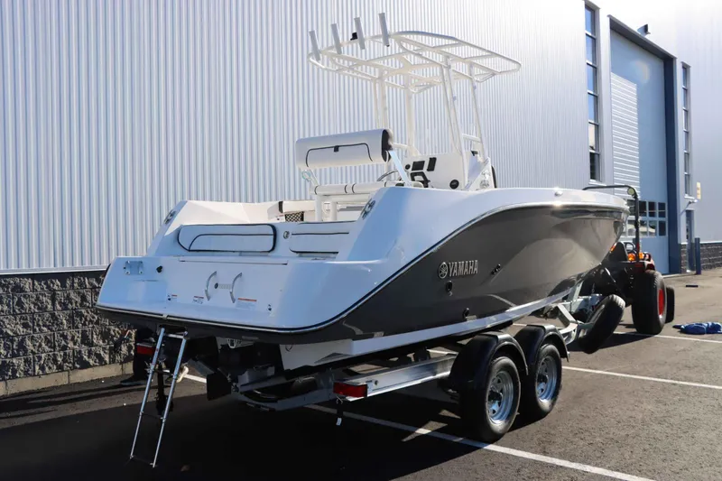 Slide: The Image of 2025 Yamaha Boats 222 FSH Sport on trailer, parked outside industrial building. - 4