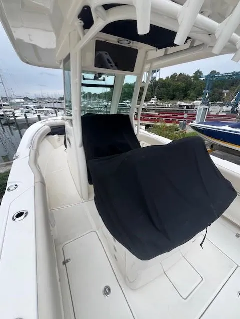 Slide: The Image of 2020 Boston Whaler 280 Outrage boat interior at marina, featuring covered seating and helm. - 13