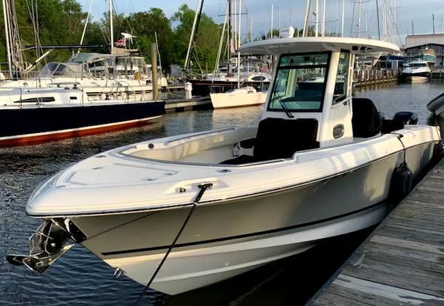 Slide: The Image of 2020 Boston Whaler 280 Outrage docked at a marina with sailboats in the background. - 2