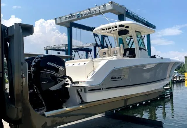 Slide: The Image of 2020 Boston Whaler 280 Outrage on a lift, featuring dual Mercury engines. - 7
