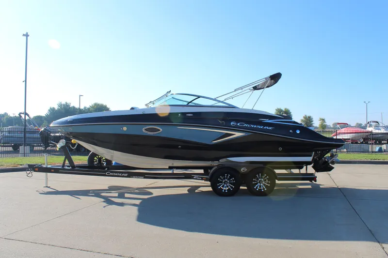 Slide: The Image of 2024 Crownline Eclipse E255 boat interior with white seating and speaker, under clear blue sky. - 34