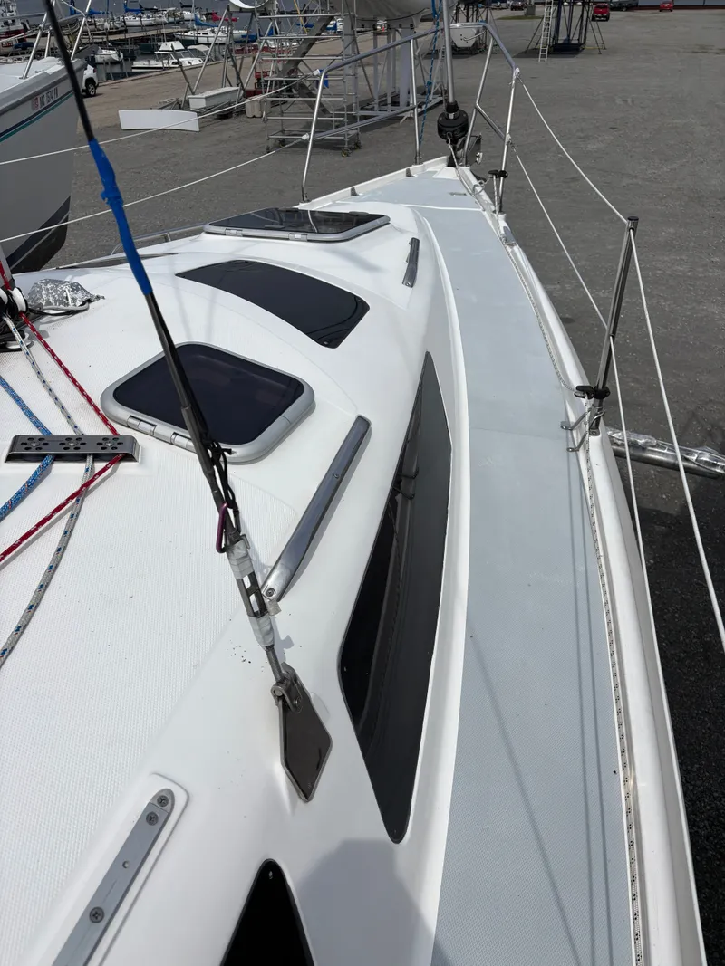 Slide: The Image of 2001 Hunter 320 sailboat deck with ropes and hatches in a marina setting. - 23