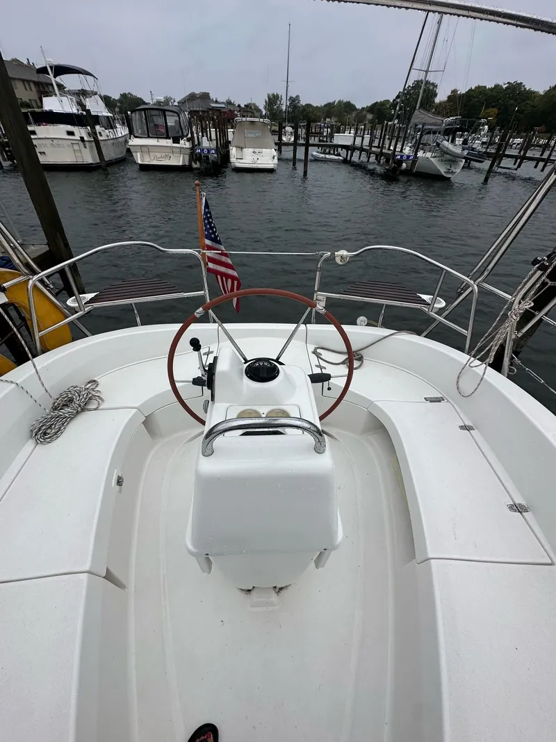 Slide: The Image of 2001 Hunter 320 sailboat cockpit with steering wheel, docked in marina, American flag visible. - 26